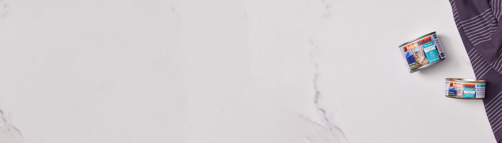 Feline Natural Beef & Hoki Cans on a marble countertop